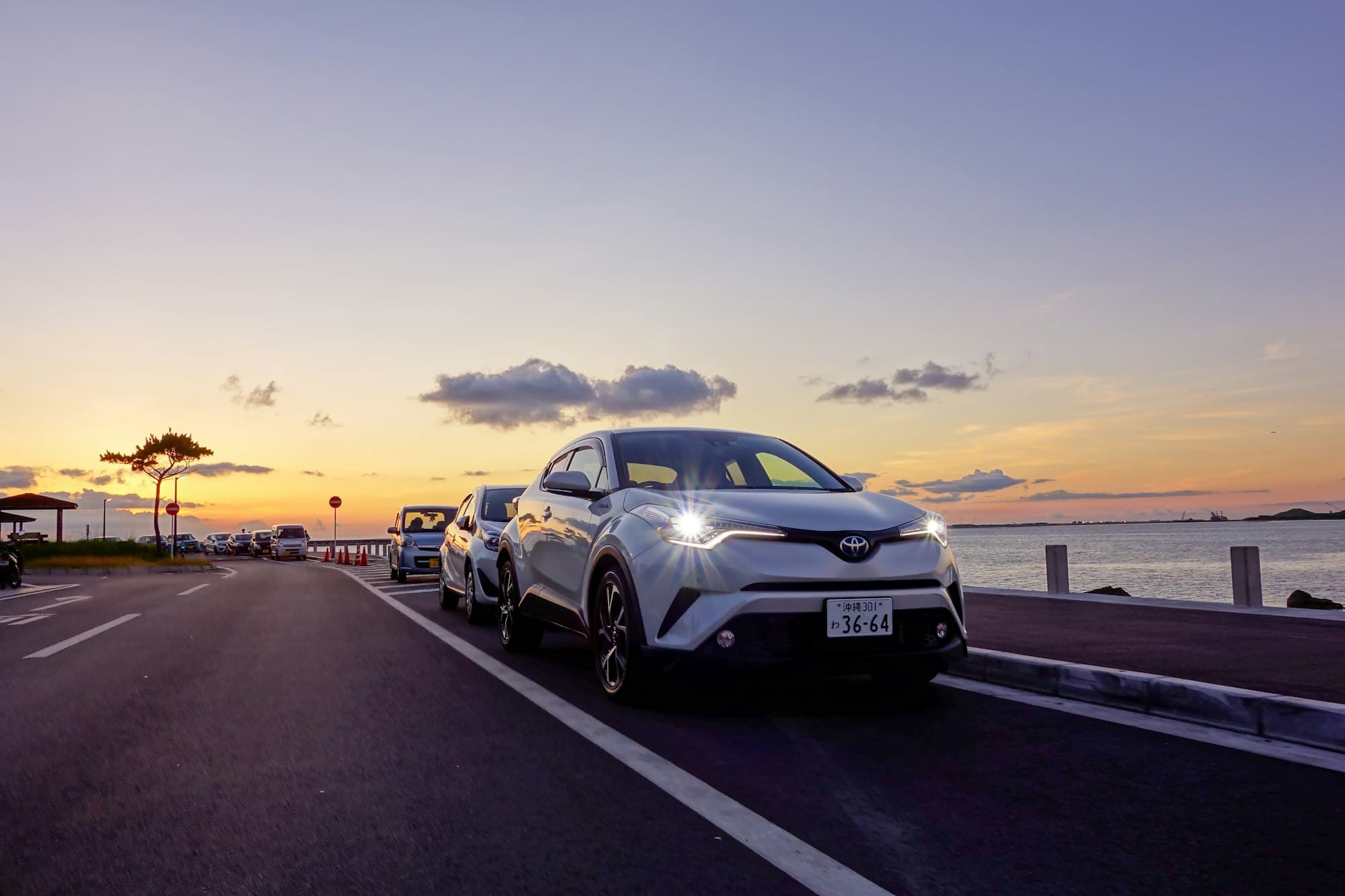 Rental car on a coastal road at sunset